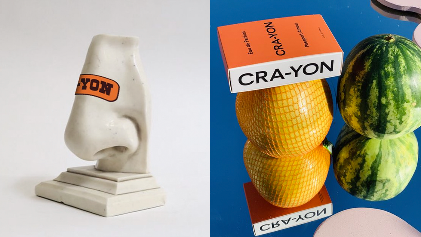 CRA-YON perfume with playful fruit stack and sculpture featuring bold orange CRA-YON label.