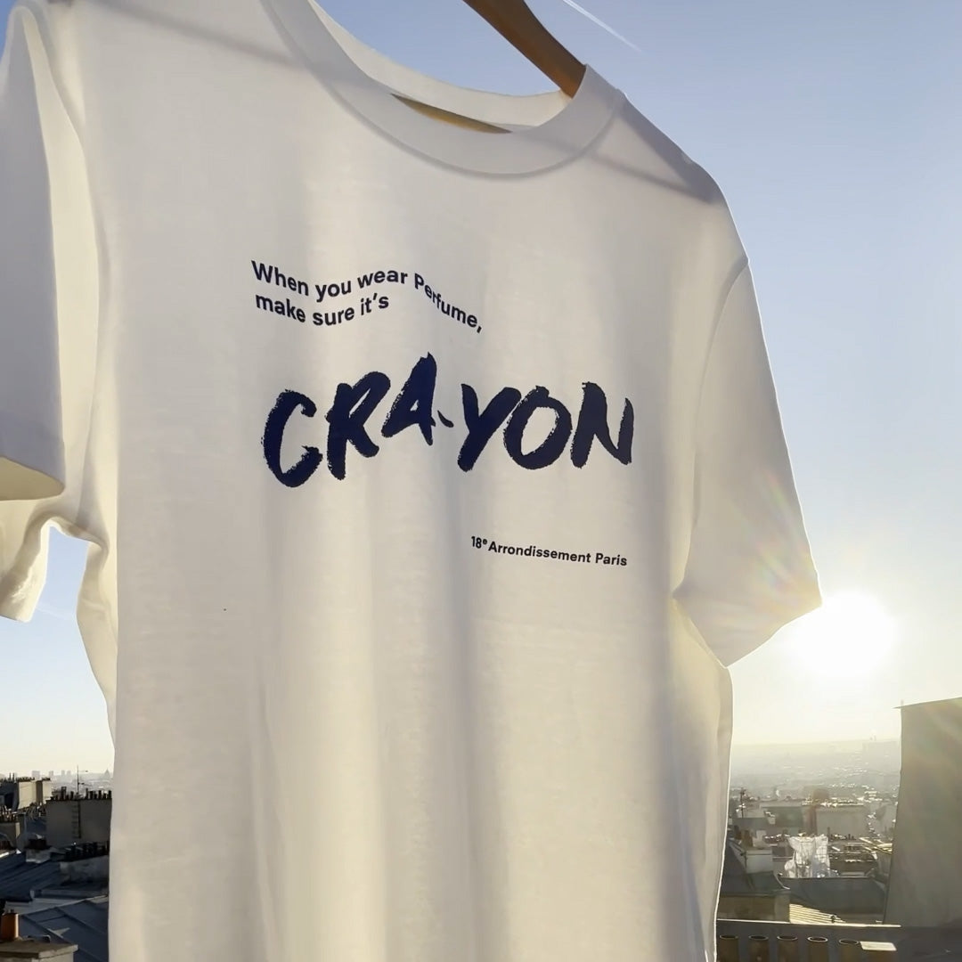 CRA-YON Perfume T-shirt – folded white t-shirt with blue logo print, sky background