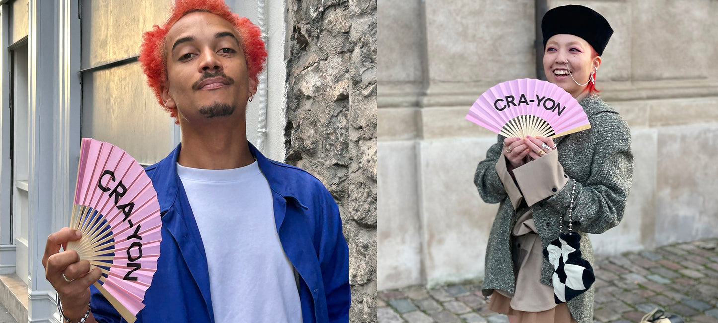 Stylish individuals holding pink CRA-YON fans showcasing streetstyle fragrance culture with playful elegance