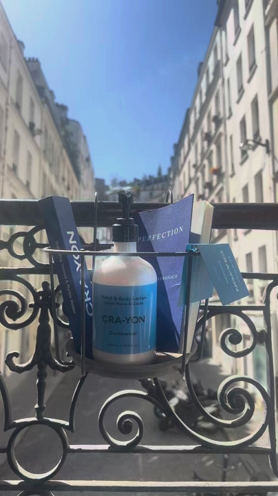 CRA-YON hand & body lotion on a Paris balcony with blue sky and city buildings in the background